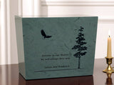 Green Katahdin urn with an eagle and tree design inscribed, text 'Forever in our Hearts We will always miss you Julian and Prudence', on a table with a candle nearby.
