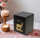 Black keepsake urn with gold deer design and 'Dad' text sitting on a decorative table with candles and flowers.