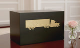 Black Seguin urn with gold truck design on a table with flowers in the background