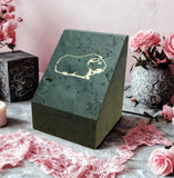 Green triangular pet urn with cream gerbil inscribed, on a pink floral background