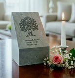 Green slate urn with tree engraving near a candle on a table