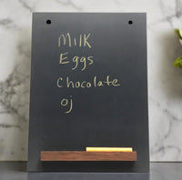 Black slate chalkboard with wooden chalk ledge and written grocery list