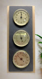 Natural Cleft Black slate 3-hole hanging Rangeley weather station on an oak background with clock, thermometer, and hygrometer with gold faces